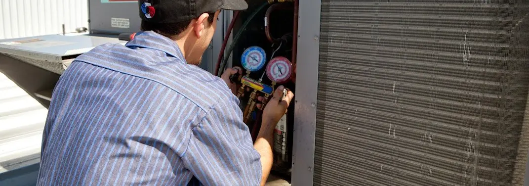 HVAC technician servicing a condenser unit in Poway